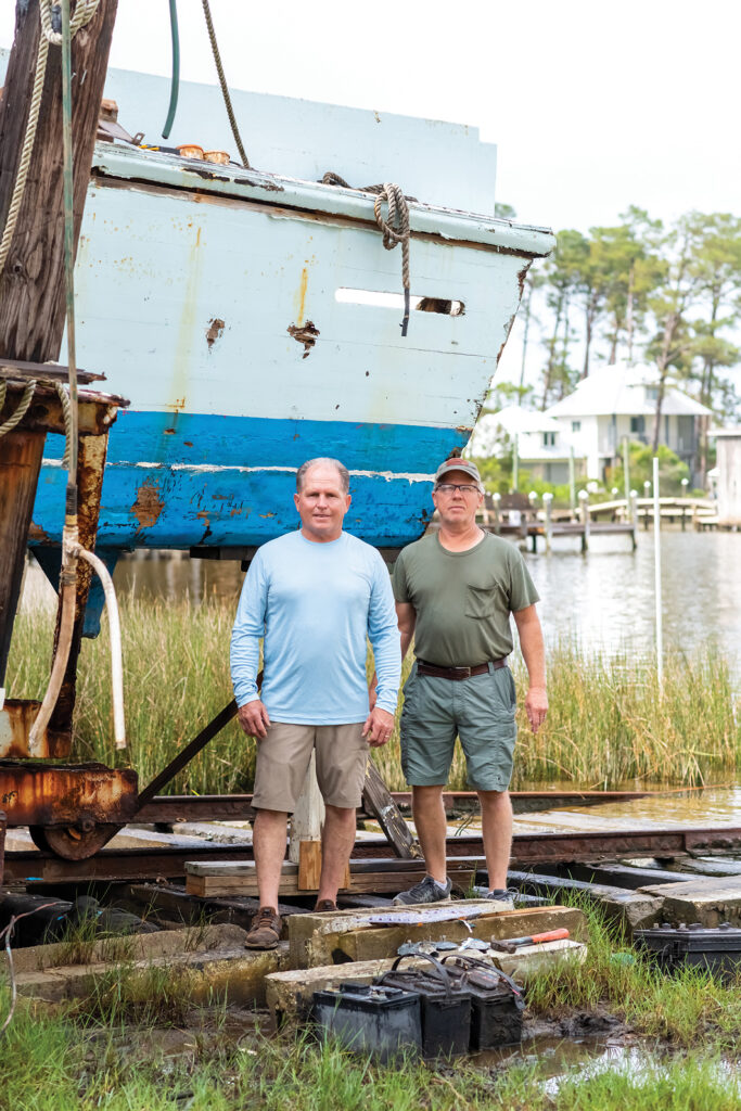 Two men standing in front of a Resmondo boat